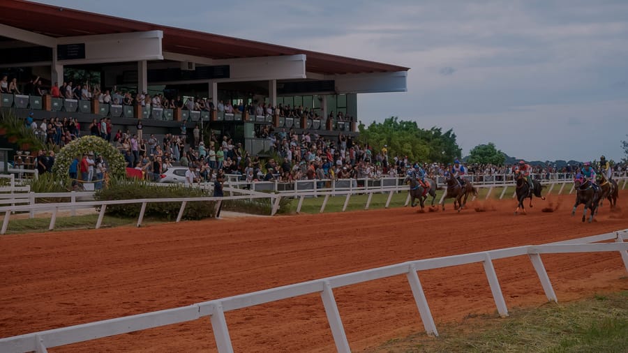 Arquibancada coberta cheia de público ao lado da pista de areia do Jockey Club de Sorocaba